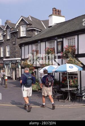 Walkers in Main Street Hawkshead villaggio popolare Lake District turistico zona a piedi associazioni con Beatrix Potter e William Wordsworth Cumbria Regno Unito Foto Stock