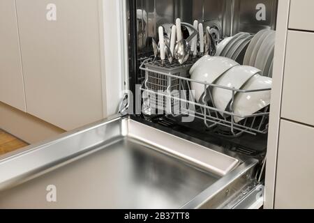 Una lavastoviglie domestica compatta piena di stoviglie bianche in una cucina moderna Foto Stock