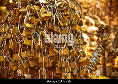 Un mucchio di golden lucchetti attaccati insieme e fissati alla recinzione. Foto Stock