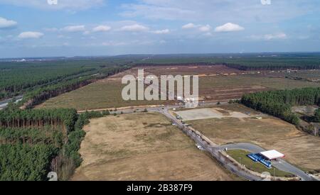 04 marzo 2020, Brandeburgo, Grünheide: Vista della zona forestale sgomberata (nella parte superiore della foto) sul sito della futura Tesla Gigafactory (foto aerea con drone). Ci si aspetta che il produttore di auto elettriche statunitense Tesla inizierà a costruire la propria fabbrica a Grünheide, nei pressi di Berlino, a marzo. Tesla sta progettando di costruire una gigafabbrica su questo sito, a est dell'autostrada A10 Berlin Ring nel comune di Grünheide. (Su 'Il Periodo per le obiezioni contro la prima fabbrica di Tesla in Europa finisce') Foto: Patrick Pleul/dpa-Zentralbild/dpa Foto Stock