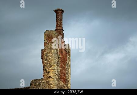 Tudor twisted orzo zucchero camino pentola su camino stack con selce, mattoni rossi e pietra di lavoro con uno sfondo di nuvola grigia con buona copia spazio. Foto Stock