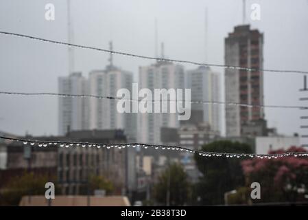 Cavo Clothesline pieno di piccole gocce in una giornata di pioggia con un fuoco selettivo su di loro e profondità di campo molto poco profonda con uno sfondo sfocato Foto Stock