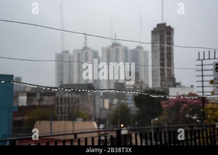 Cavo Clothesline pieno di piccole gocce in una giornata di pioggia con un fuoco selettivo su di loro e profondità di campo molto poco profonda con uno sfondo sfocato Foto Stock