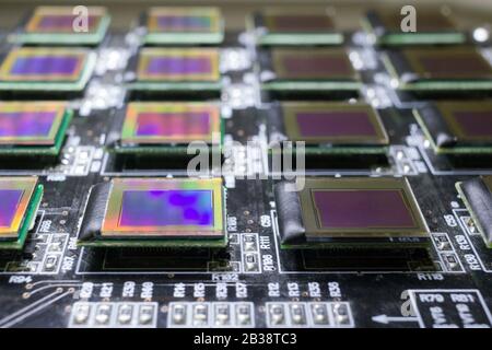 Il processo di controllo di diversi display oled sulla stazione di test. I monitor si spengono e hanno l'arcobaleno sulla superficie. Foto Stock