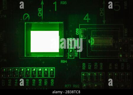 Il processo di controllo di diversi display oled sulla stazione di test. Mostra un'illuminazione di colore verde in primo piano. Foto Stock