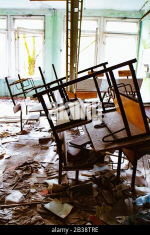 Scena caotica con banchi impilati in una sala scuola della scuola elementare abbandonata numero 3 a Pripyat, Ucraina, zona di esclusione di Chernobyl. Foto Stock