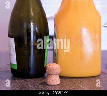 Una bottiglia di champagne e una bottiglia di succo d'arancia su un tavolo con un tappo di sughero. Foto Stock