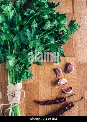 freschezza prezzemolo, aglio e peperoni rossi . Mazzetto di prezzemolo, erba biologica verde. Ingrediente vegetale per cibi sani e gustosi. Foto Stock