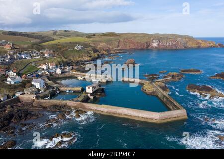 Veduta aerea del piccolo villaggio di pescatori e del porto di St Abbs sulla costa del Mare del Nord nei Confini scozzesi, Scozia, Regno Unito Foto Stock