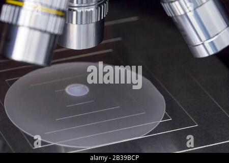 Primo piano di esame di un campione di wafer di zaffiro sotto il microscopio in laboratorio.UN semiconduttore su un wafer di silicio. Messa a fuoco selettiva. Foto Stock