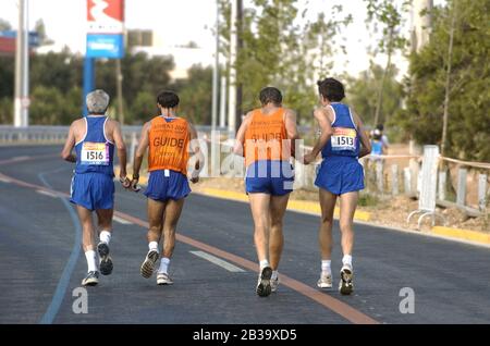 Atene, Grecia 26 SET 2004: Atene, Grecia: Corridori greci (1513) a sinistra, Stergios Sioutis e (1516), a destra, Konstantinos Stavriois che corrono con le loro guide a metà della maratona maschile T11 per corridori ciechi al Paralimpico. ©Bob Daemmrich Foto Stock