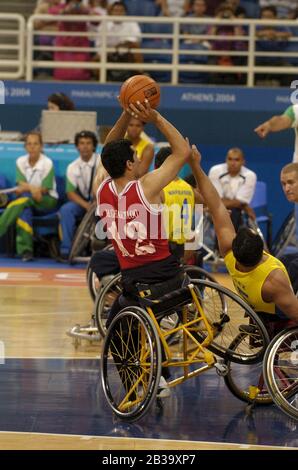 Atene, Grecia 26 SET 04: Azione di pallacanestro per carrozzella da uomo Paralympics tra Brasile (giallo) e Iran (rosso). ©Bob Daemmrich Foto Stock