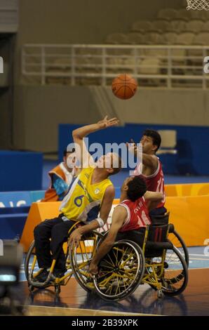 Atene, Grecia 26 SET 04: Azione di pallacanestro per carrozzella da uomo Paralympics tra Brasile (giallo) e Iran (rosso). ©Bob Daemmrich Foto Stock