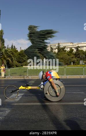 Atene, Grecia 26 SET 2004: Il maratoniere in sedia a rotelle passa la statua di Phidippides ad Atene, in Grecia per finire la fila durante i Giochi Paralimpici. ©Bob Daemmrich Foto Stock