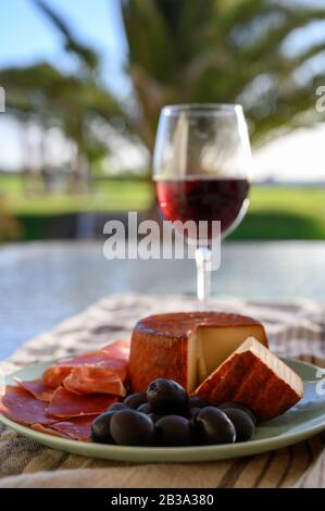 Sapori di Spagna, jamon iberico, olive nere, formaggio manchego con la paprica rossa e vetro con rosso vino Rioja chiudere fino a luci di Sun Foto Stock