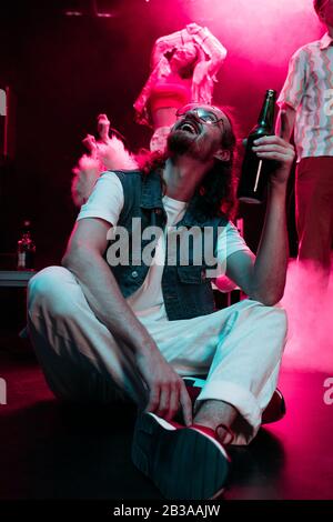 ragazza felice con una bottiglia di alcol durante la rave in discoteca Foto  stock - Alamy