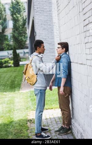 ragazzo americano africano in felpa con cappuccio e jeans che gonfia ragazzo in occhiali Foto Stock