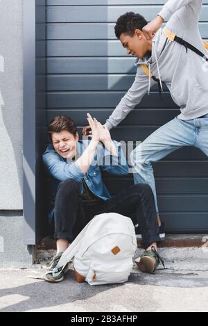 ragazzo americano africano in felpa con cappuccio e jeans che pugni il ragazzo spaventato Foto Stock