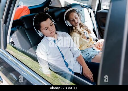 fuoco selettivo di cute bambini in cuffie che dormono in auto Foto Stock