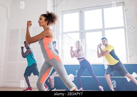 Fuoco selettivo di addestratore americano africano che pratica i movimenti con i ballerini multietnici zumba nello studio di ballo Foto Stock