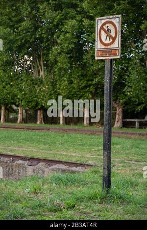 Un segno arrugginito che indica 'nessun passaggio pedonale' circondato da erba verde e alberi sullo sfondo Foto Stock