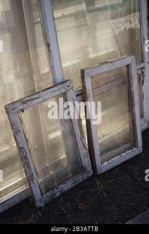 vecchie finestre sporche con cornici di legno bianche rimosse dalle aperture durante la riparazione Foto Stock