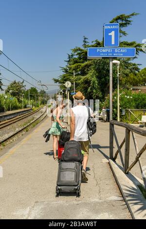 Pompei, VICINO NAPOLI, ITALIA - AGOSTO 2019: Persona che tira una valigia lungo la piattaforma 1 della stazione di Pompei Scavi Foto Stock