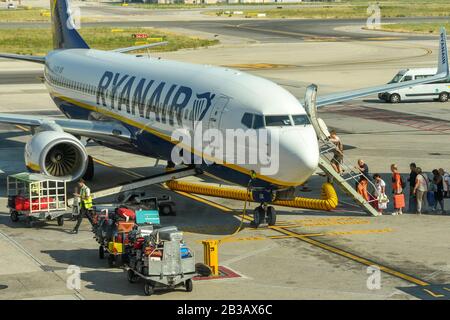 Napoli, Italia - Agosto 2019: i passeggeri di salire a bordo della Ryanair Boeing 737 jet all'aeroporto di Napoli. Il bagaglio viene caricato da carrelli per bagagli Foto Stock