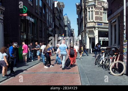 Vista sulle persone che camminano su Warmoesstraat Street ad Amsterdam. E' una delle strade piu' antiche con molti caffe', ristoranti e negozi. È una somma soleggiata Foto Stock