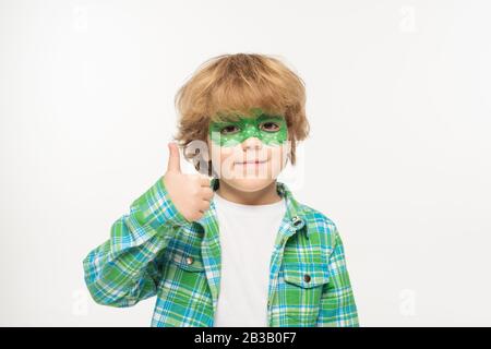 allegro ragazzo con maschera gecko dipinta sul viso che mostra il pollice in alto guardando la fotocamera isolato su bianco Foto Stock