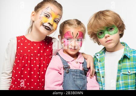 amici sorridenti con dipinti colorati che guardano la macchina fotografica isolata su bianco Foto Stock