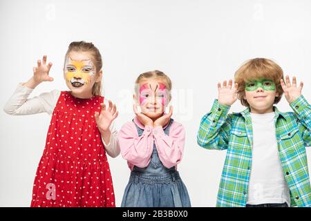 amici allegri con dipinti colorati che mostrano gesti spaventosi guardando la fotocamera isolata su bianco Foto Stock