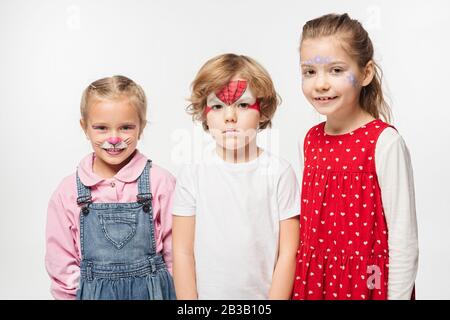 bambini allegri e ragazzo offeso con dipinti colorati che guardano la macchina fotografica isolata su bianco Foto Stock