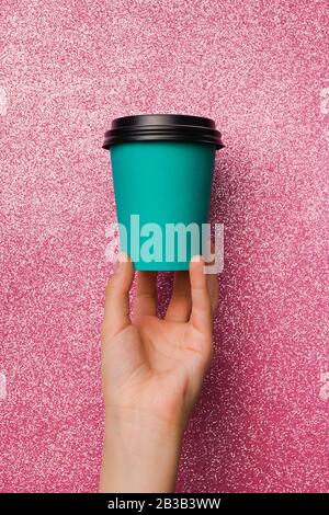 Tazza da caffè in carta blu dal design a disposizione semplice e piatta, isolata a mano su sfondo rosa brillante e colorato alla moda. Foto Stock