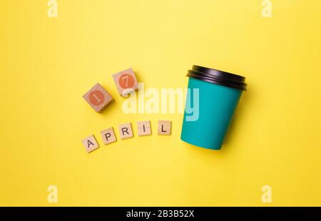 Semplice flatlay design carta blu tazza caffè e data 14 aprile isolato su giallo colorato sfondo moda. Giornata mondiale del caffè. Foto Stock