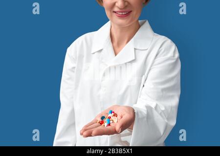 Il medico medio anziano della donna che tiene le pillole differenti in mano Foto Stock