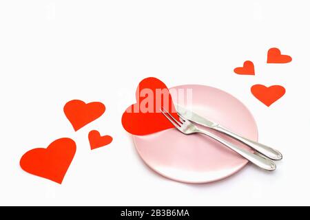 Giorno di San Valentino (o matrimonio) con forchetta e coltello, cuori di carta su sfondo bianco. Foto Stock