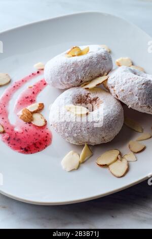 Ciambelle di torta di zucchero in polvere con buchi serviti con confettura di lamponi e mandorle scivolate Foto Stock