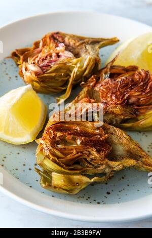 Carciofi fritti italiani tagliati a metà con spicchi di limone Foto Stock