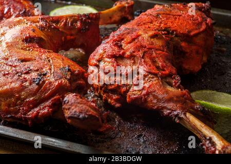 Cucina indiana piccante rosso Tandoori pollo con lime a fette su teglia da forno Foto Stock