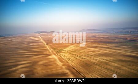 Veduta aerea del campo agricolo arato in prospettiva, vista ad alto angolo del terreno arabile. Strada sterrata attraverso i campi. Terra coltivata sulle colline di P. Foto Stock