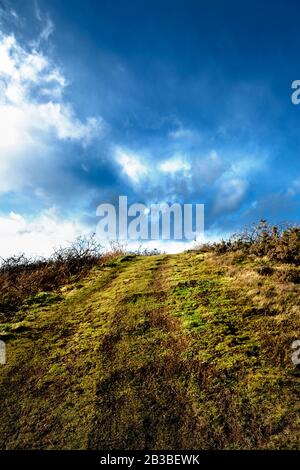 Sentiero in salita verso il cielo blu e le nuvole bianche davanti, nel Golf Club Aberdeen con nuvole e campo d'erba. Nigg Bay, Scozia. Foto Stock