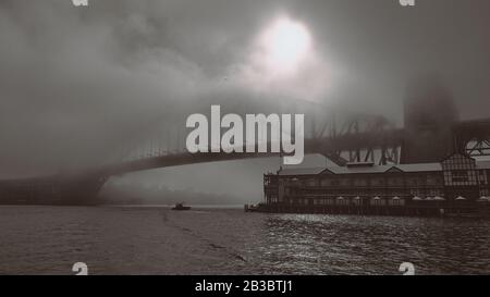 Nebbia mattutina sul Sydney Harbour Bridge come barca da pesca solitaria e un approccio di gabbiano in bianco e nero Foto Stock