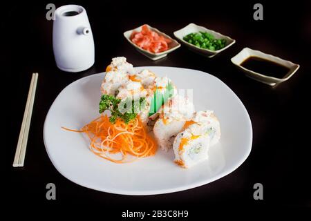 Involtini di sushi con salsa di soia su sfondo nero Foto Stock