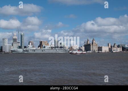 Il Mersey Ferry Royal Iris passa davanti alla compagnia aerea Prince of Wales della Royal Navy, ormeggiata presso il lungomare storico di Liverpool, patrimonio dell'umanità dell'UNESCO, sul Th Foto Stock