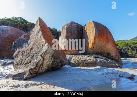 Sole che getta ombre su enormi bolder arancione a Squeaky Beach a Wilsons Prom, Victoria, Australia Foto Stock