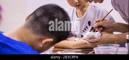 Pechino, СHINA - 01 GIUGNO 2019: I bambini cinesi imparano a dipingere con giocattoli in ceramica fatti in casa. Foto Stock