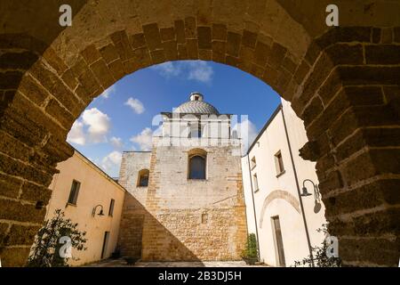 La cupola e la chiesa di San Michele Arcangelo si vedono attraverso un muro di mattoni ad arco nella città di Brindisi, in Italia, nella regione Puglia. Foto Stock