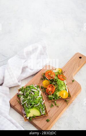 Toast di segale avocado con erbe verdi, cipolla e pomodori ciliegini, cibo sano Foto Stock