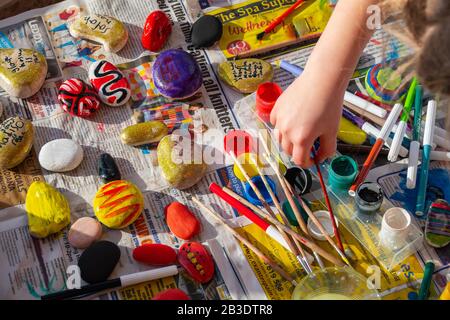 Bambino pittura rocce con acquerelli sul giornale, luminoso con un sacco di colori. Foto Stock